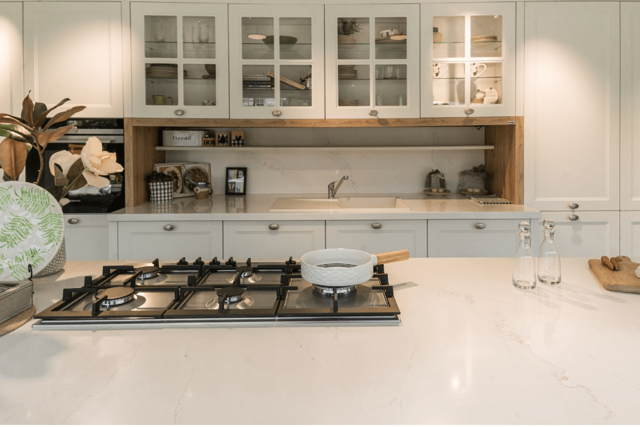 Small kitchen features grey-blue cabinets, black and white wallpaper mural, & white tile backsplash.